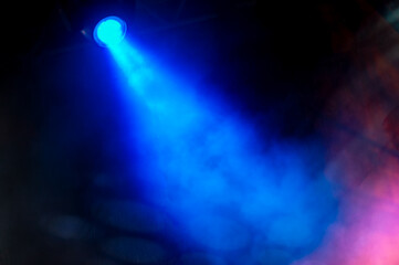 On the dark background, the blue light of the spotlights on the stage.