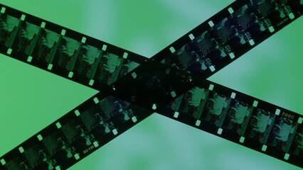 Crossed stripes of photographic film on green background close up. Negatives of photographic film...