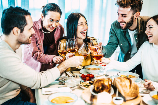 Happy Smiling Friends Toasting Rosé Wine Glasses At Dinner Party - Group Of People Having Lunch Break At Bar Restaurant - Life Style Concept With Guys And Girls Hanging Out Together