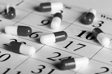 black and white medical pills on calendar background