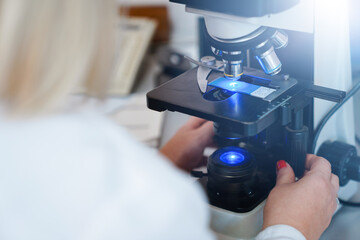 Female scientist using microscope in laboratory.  Biotechnology specialist looking under...