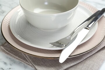 Clean plates, bowl, cutlery and napkin on table, closeup