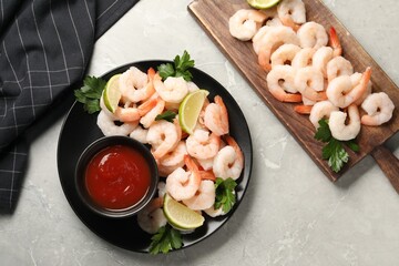Tasty boiled shrimps with cocktail sauce, parsley and lime on light grey table, flat lay