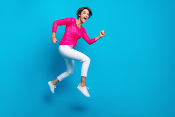 Fototapeta na wymiar Full length photo of cheerful positive woman wear knitted neon shirt jumping high running empty space isolated blue color background