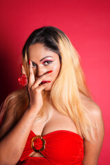 a beautiful young woman in red dress on red background, covering her face with hands