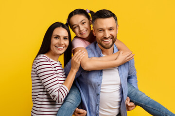 Loving family with daughter on father's back enjoying fun moment