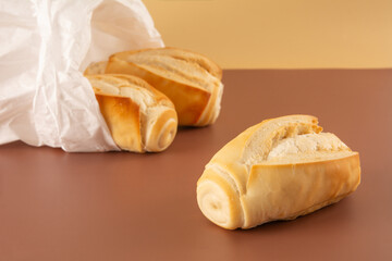 Fresh baked flour bread in paper bag in brown and beige background in front view angle with empty blank space