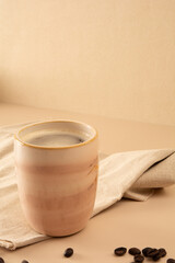 Coffee mug in a beige background with coffee beans and table cloth in front view