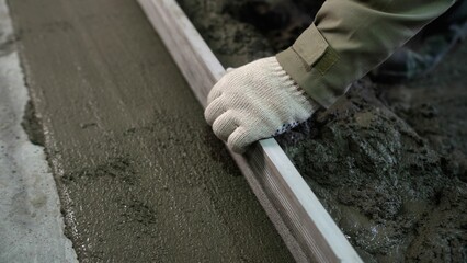 A builder uses a trowel to level a cement mortar screed. Concrete work on a construction site....