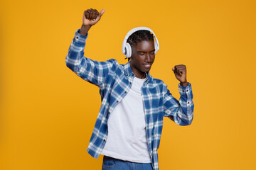 Positive young black man enjoying listening music, dancing and having fun