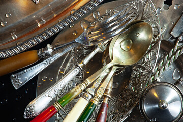 Antique silver cutlery on a dark background in a composition on a table.
