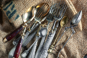 Antique silver cutlery, forks, spoons, knives, in a composition on a black background.