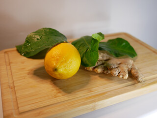 Lemon with green leaves and ginger on a wooden board
