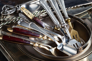 Antique silver cutlery, forks, spoons, knives, in a composition on a black background.