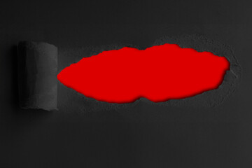 Obraz premium Black construction paper torn in the middle with a red background inside