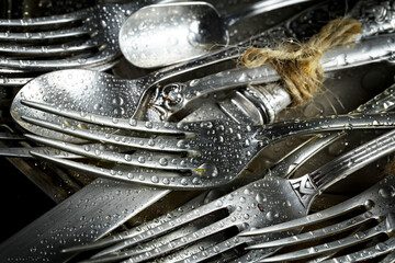 Antique silver cutlery on a dark background in a composition on a table.
