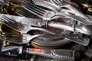 Antique silver cutlery on a dark background in a composition on a table.