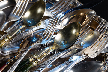 Antique silver cutlery on a dark background in a composition on a table.
