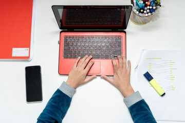 Overhead shot capturing a preadolescent's hands skillfully typing on a laptop