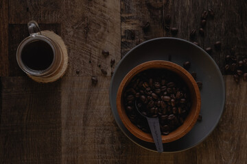 Obraz na płótnie Canvas Top view of a wooden bowl with coffee beans near a cup of coffee