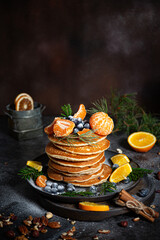 Pile of pancakes with oranges on a plate on dark background 