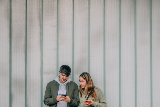 urban young couple with mobile phones on the street wall
