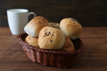 籠にいれ木製テーブルにおいた様々なパン