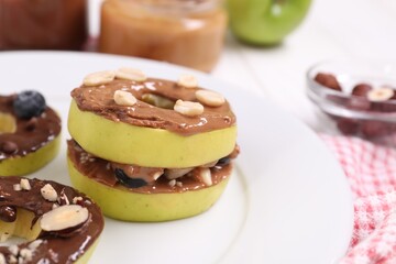Fresh apples with nut butters and peanuts on plate, closeup