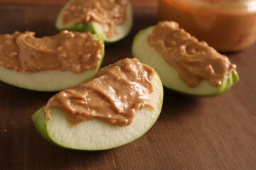 Slices of fresh apple with nut butter on wooden board, closeup