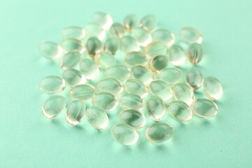Many vitamin capsules on turquoise background, closeup