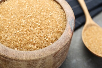 Brown sugar in bowl on grey table, closeup