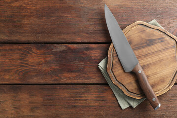 One sharp knife and board on wooden table, top view. Space for text