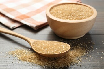 Brown sugar in bowl and spoon on wooden table, closeup