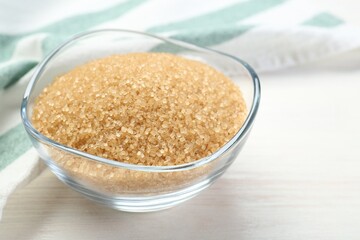 Brown sugar in glass bowl on white wooden table, closeup