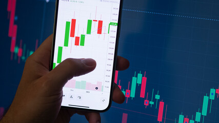 Crypto trader investor broker holding finger using cell phone app executing financial stock trade market at the night. Dark theme, close up shot. - obrazy, fototapety, plakaty