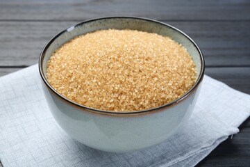 Brown sugar in bowl on black wooden table, closeup