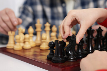 Grandfather and grandson playing chess at table, closeup