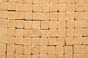 Brown sugar cubes as background, top view