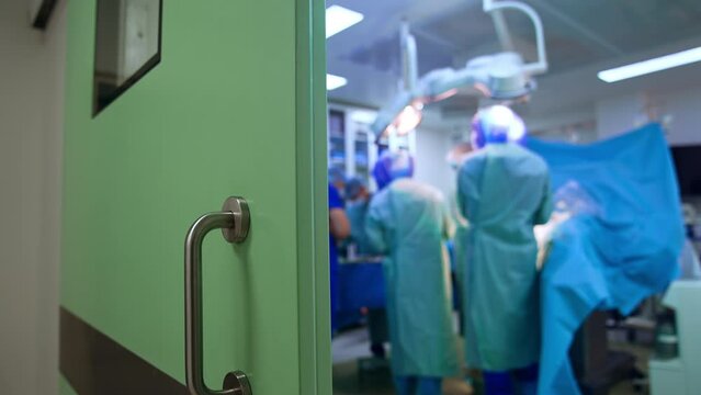Opened door to a surgery room with operation in progress. Close up. Blurred backdrop.