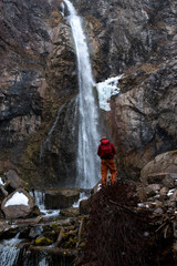 Hiker in front of a snowy waterfall