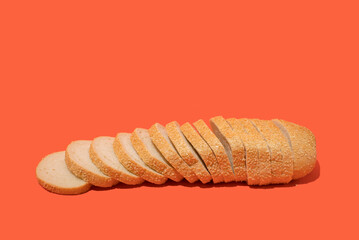 Side view of arranged slices of fresh white bread with sesame seeds against orange background. Bakery concept