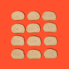 Top view of arranged slices of fresh white bread with sesame seeds against orange background. Bakery concept