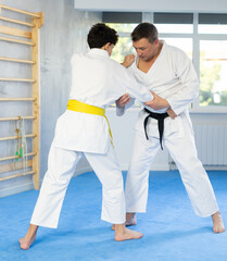 Fototapeta premium Individual judo lesson for teenager - guy and trainer are sparring in the gym