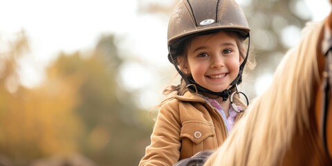Equitation lesson. Happy child girl while riding a horse - obrazy, fototapety, plakaty
