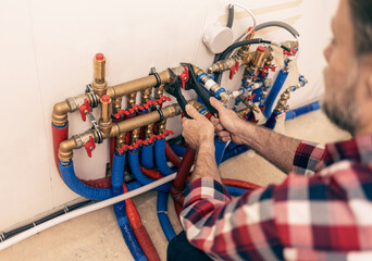 Domestic water installation - plumber tightens a valve on a water pipes. Construction site -...