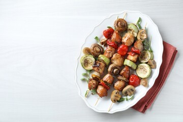 Delicious shish kebabs with vegetables and microgreens on white table, top view. Space for text