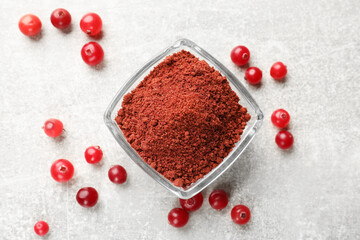 Cranberry powder in bowl and fresh berries on light grey table, top view