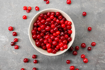Fresh ripe cranberries in bowl on grey table, top view