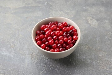Fresh ripe cranberries in bowl on grey table