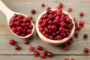 Fresh ripe cranberries in bowl and spoon on wooden table